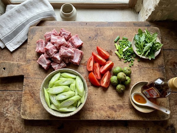 Mâm nguyên liệu nấu canh sườn chua gồm sườn non dẻ tươi dọc mùng sấu xanh cà chua