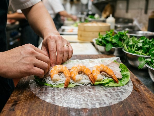 Đầu bếp xếp tôm thịt rau bún và cuốn chặt tay gỏi cuốn trên thớt