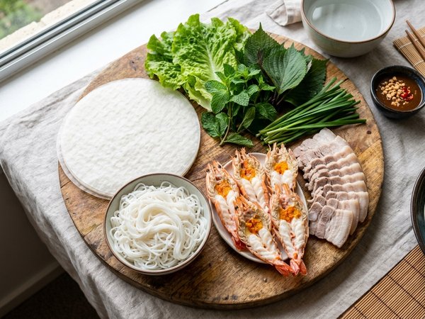 Mâm nguyên liệu làm gỏi cuốn tôm thịt gồm tôm luộc xẻ đôi thịt ba chỉ luộc và rau thơm